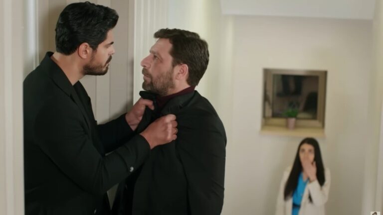 Cihan chwyta Nusreta za marynarkę. Hancer stoi na półpiętrze, skąd obserwuje scenę.