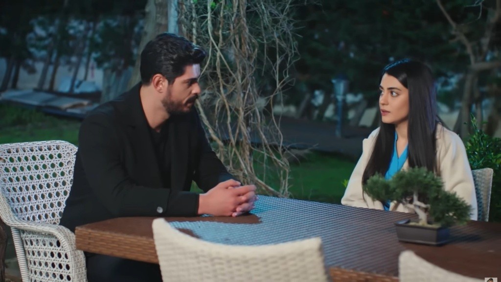 Wieczór. Cihan i Hancer siedzą przy stoliku przed starym domem.