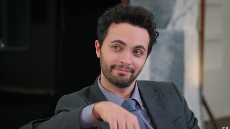 Engin spogląda z delikatnym, rozbawionym uśmiechem.