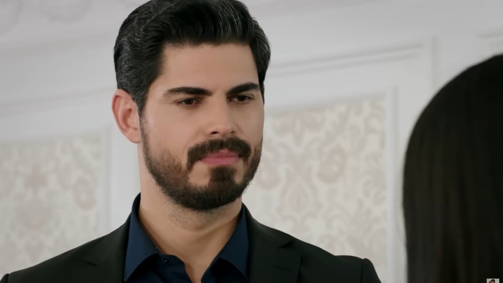 Zbliżenie na twarz Cihana, która emanuje powagą, lecz jednocześnie ujawnia ciepło i zrozumienie w jego oczach.