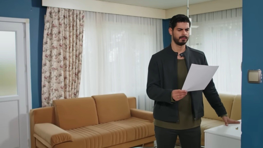 Cihan stoi w salonie starego domu. Trzyma w rękach zostawioną przez Hancer kartkę.