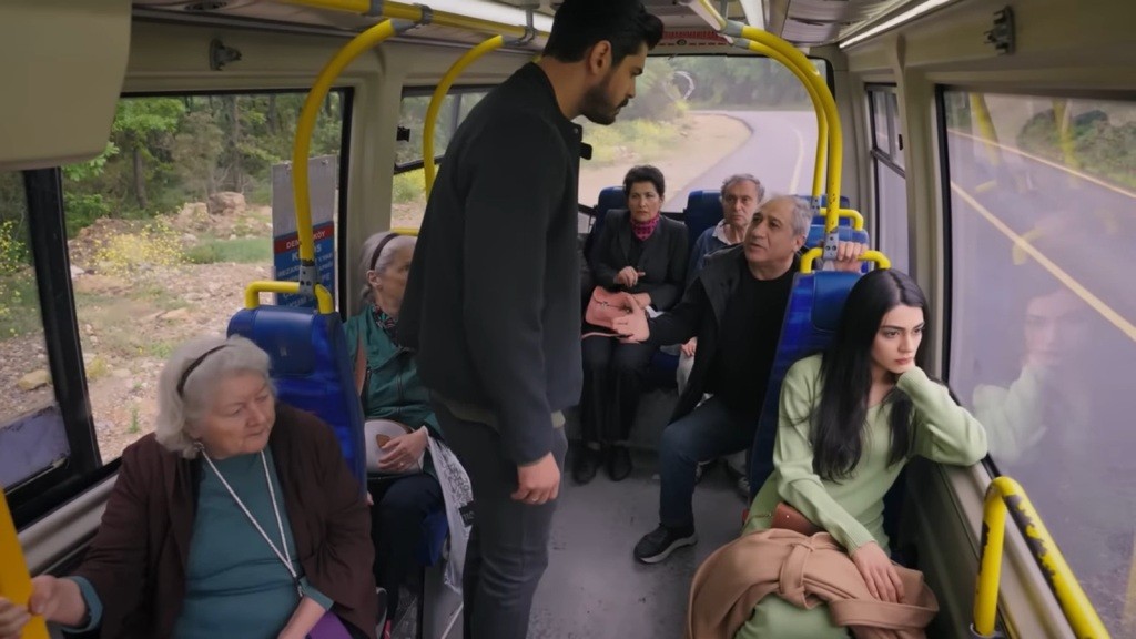 Cihan wkracza do autobusu. Zatrzymuje się obok siedzącej przy oknie Hancer.