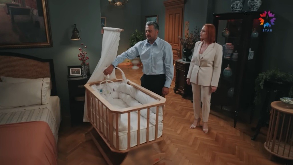 Orhan stoi obok dziecięcego łóżeczka. Za jego plecami stoi Ifakat.