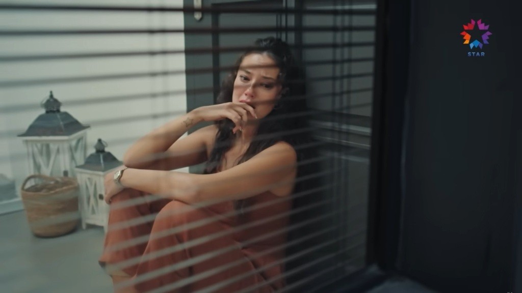 Diyar siedzi na podłodze, opierając się o drzwi.