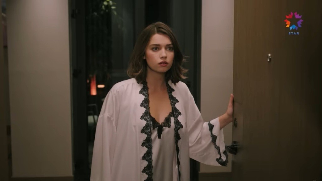 Seyran otwiera drzwi, ubrana w koszulę nocną.