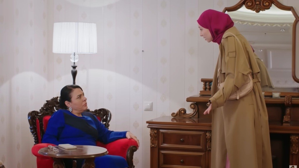 Mukadder siedzi w fotelu. Sinem stoi przed nią, rozkładając ręce.