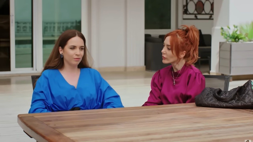 Beyza i Yonca siedzą przy stole na zewnątrz rezydencji.