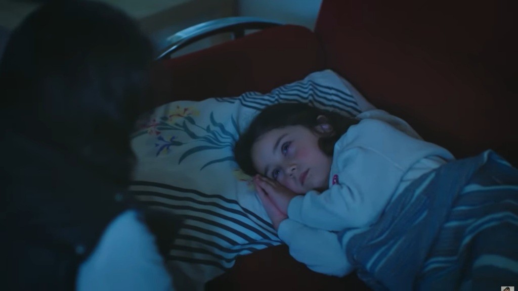 Mine otwiera oczy. Śpi na kanapie, z głową przytuloną do poduszki. Obok kanapy kuca jakiś mężczyzna. On i Mine patrzą na siebie.