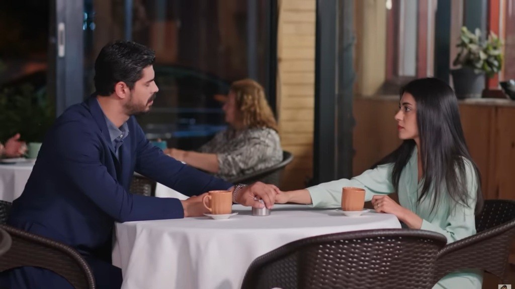 Cihan i Hancer siedzą przy stoliku w kawiarni. Mężczyzna trzyma ją za rękę.