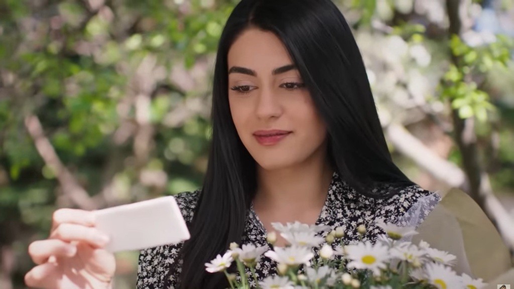 Hancer trzyma w rękach bukiet margaretek i czyta dołączony liścik.