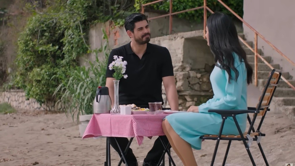 Cihan i Hancer siedzą przy stoliku na plaży.