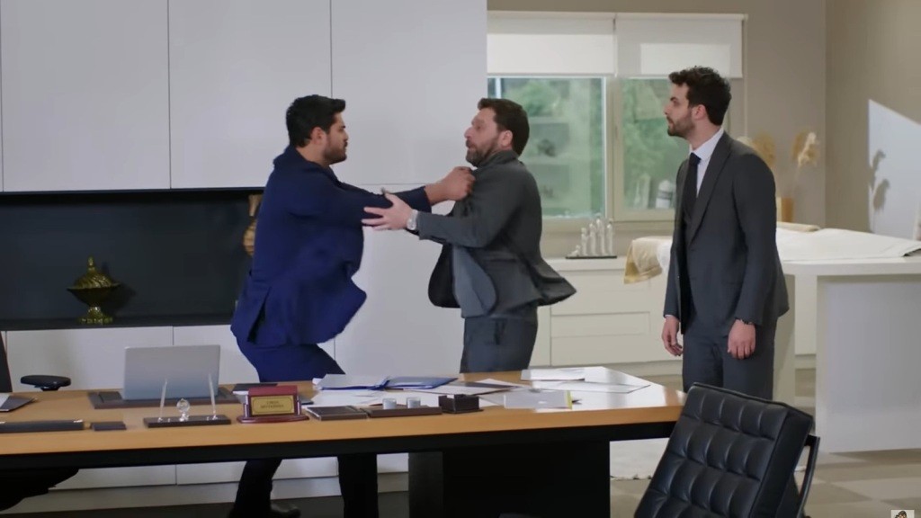 Cihan i Nusret szarpią się przy biurku. Engin stoi tuż obok.