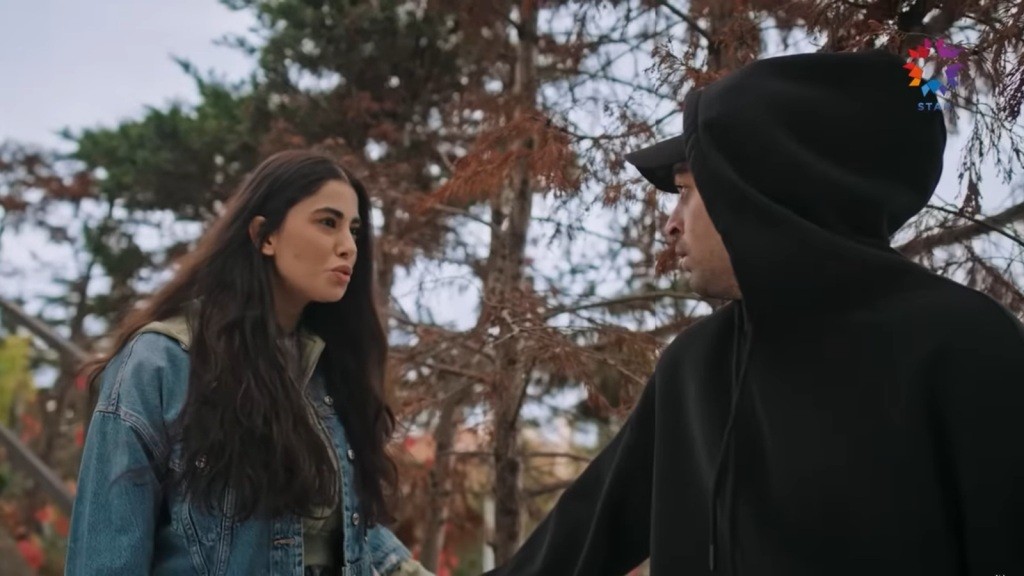 Sinan, ubrany w czarną bluzę z kapturem, odwraca się. Przed nim stoi Aysen.