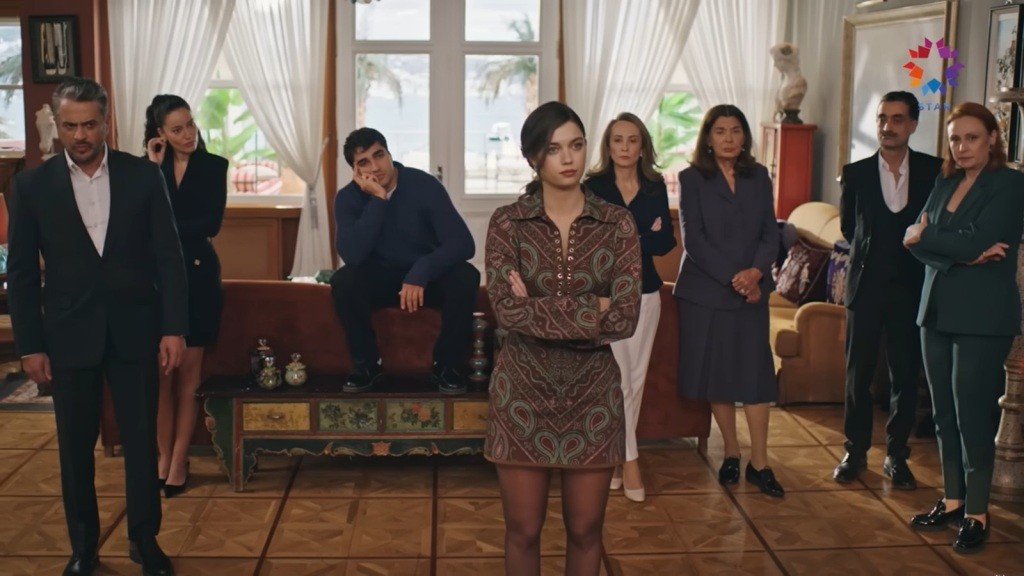 Seyran stoi na środku salonu ze skrzyżowanymi na piersi rękami. Za jej plecami znajdują się jej rodzice, ciocia Hatice i Korhanowie.