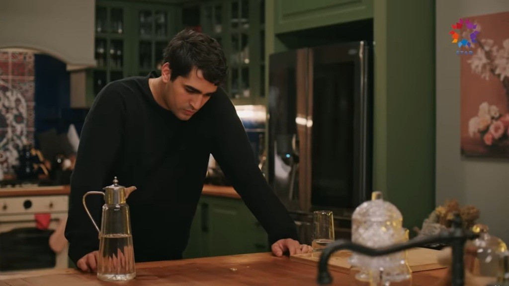 Ferit opiera się rękoma o wyspę i patrzy na leżącą na blacie obrączkę.