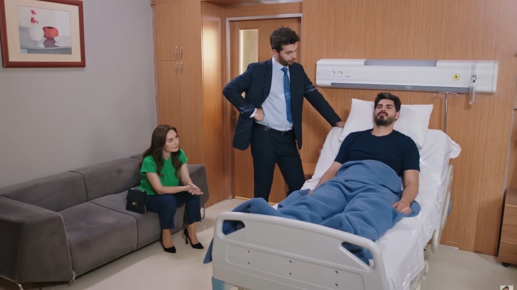Sala szpitalna. Engin stoi przy łóżku Cihana, a Yasemin siedzi na sofie.