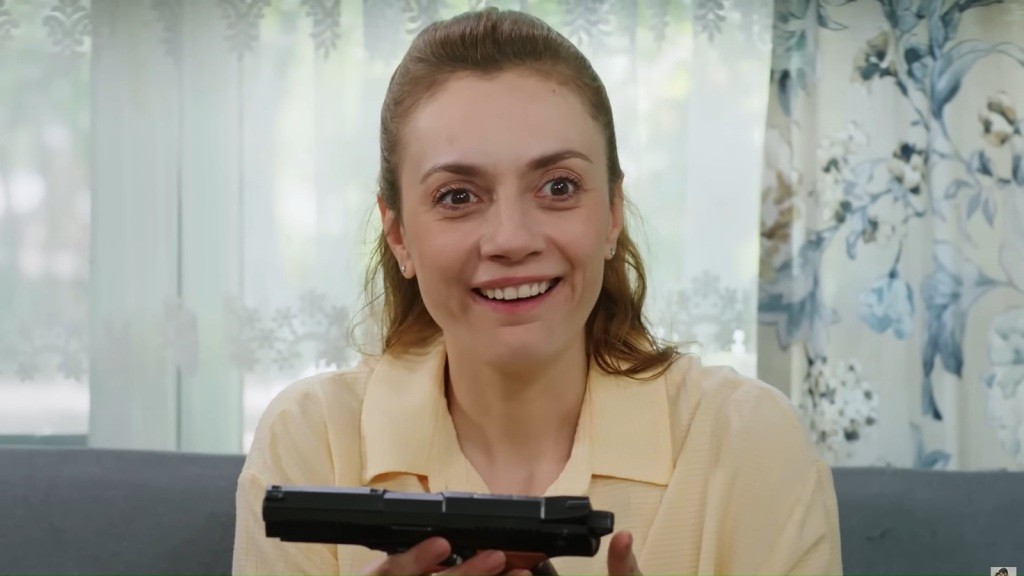 Derya trzyma w rękach zabawkowy pistolet. Uśmiecha się do własnych myśli.