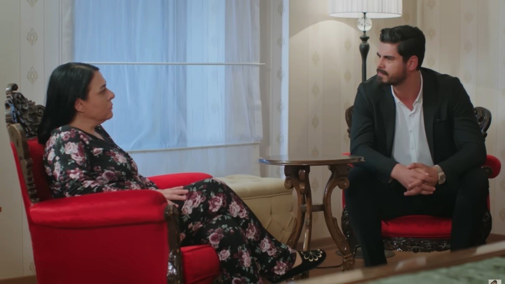 Mukadder i Cihan siedzą w czerwonych fotelach. Mężczyzna mierzy matkę groźnym wzrokiem.