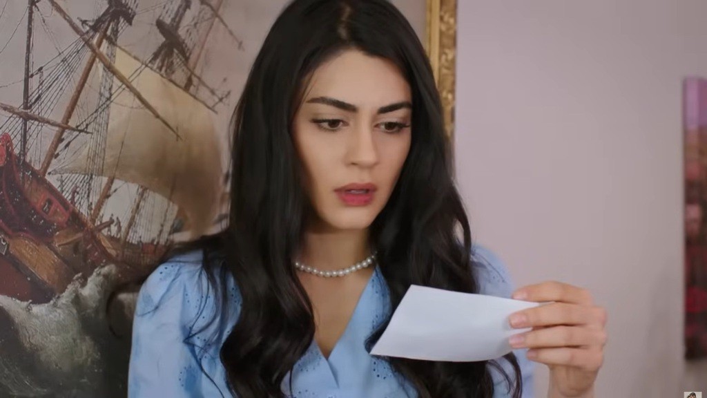 Hancer trzyma zdjęcie w ręku i wpatruje się w nie z wyrazem szoku na twarzy.