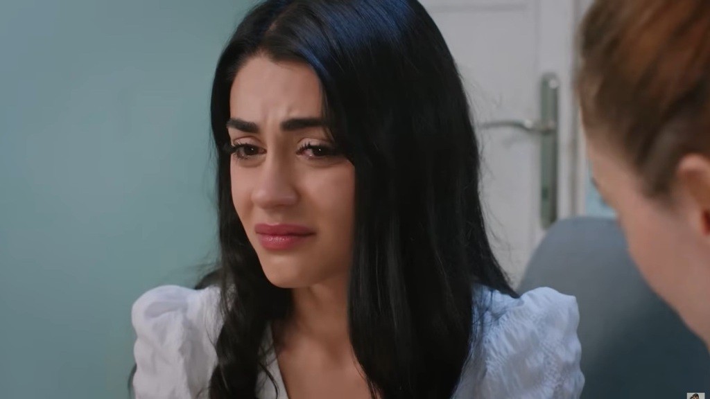 Hancer jest bardzo przygnębiona. Z boku kadru widać fragment twarzy Deryi.