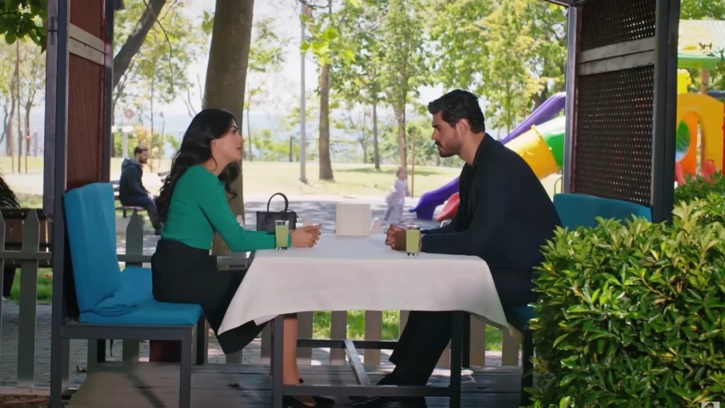 Hancer i Cihan siedzą naprzeciwko siebie przy stoliku w kawiarni.