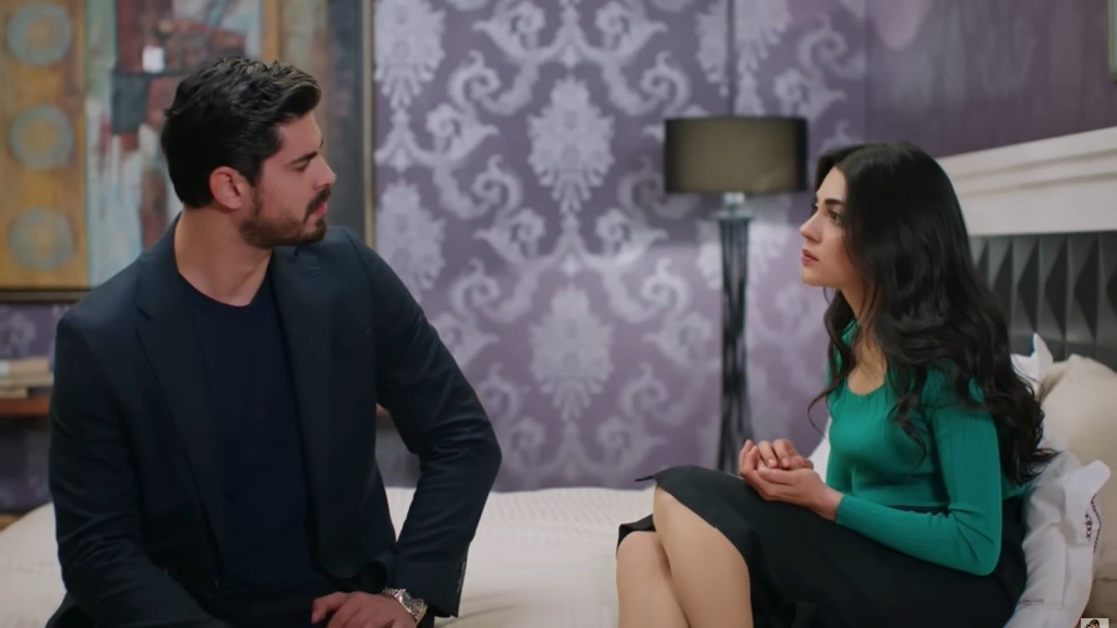 Cihan i Hancer siedzą na skraju łóżka, zwróceni do siebie twarzami.