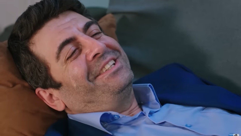 Leżący na kanapie Cemil uśmiecha się.