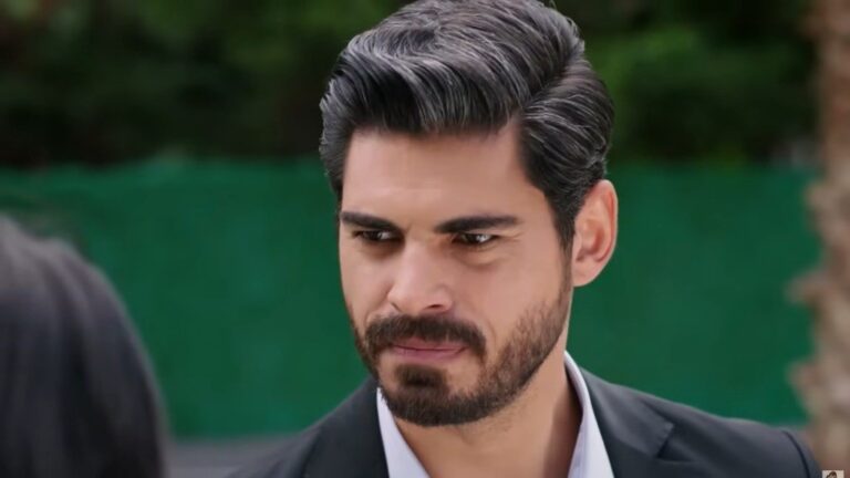 Zbliżenie na poważną twarz Cihana na tle zieleni — elegancki, stonowany kadr.