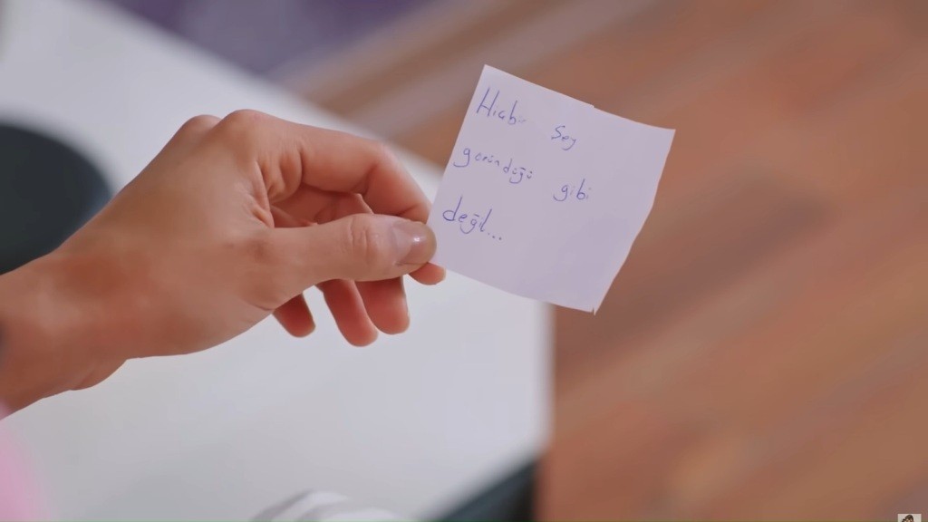 Zbliżenie na karteczkę z wiadomością w ręku Hancer.