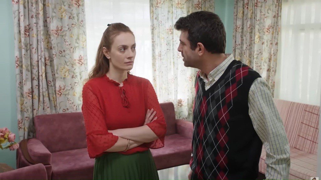 Derya stoi przed mężem ze skrzyżowanymi rękami.