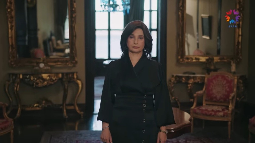 Wielka Dama stoi na środku przedpokoju w swojej posiadłości.