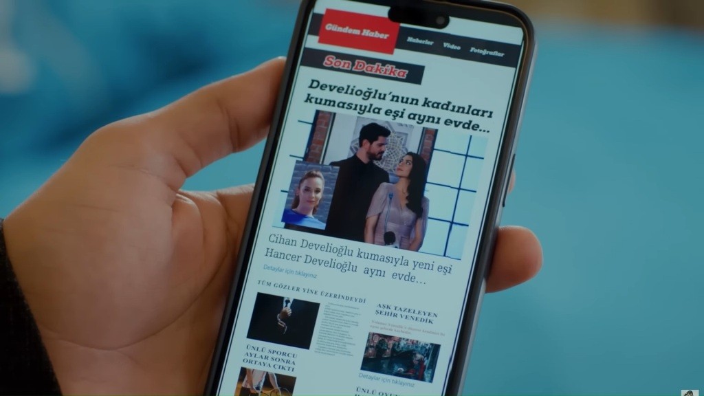 Zbliżenie na ekran telefonu Cihana. Wyświetlony jest na nim artykuł, opisujący to, że mieszka z dwiema żonami pod jednym dachem.