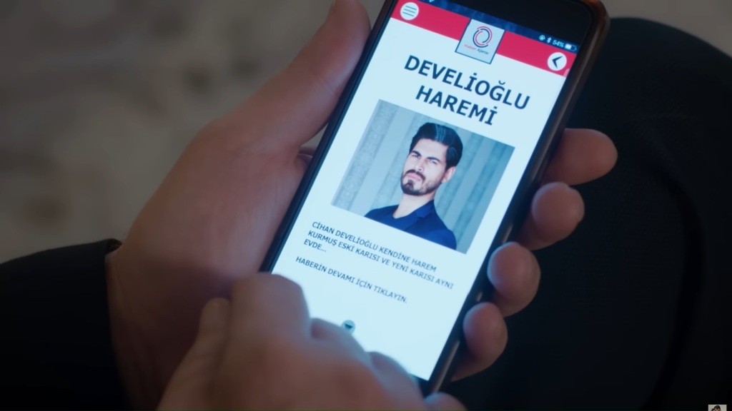 Zbliżenie na telefon w rękach Nusreta. Na jego ekranie wyświetlony jest artykuł opatrzony zdjęciem Cihana.