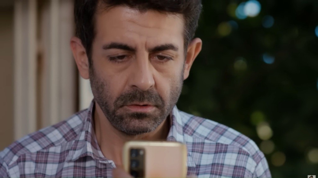 Zszokowany Cemil wpatruje się w ekran telefonu.