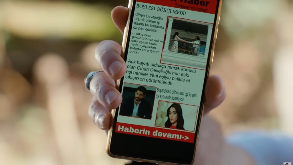 Zbliżenie na ekran telefonu, na którym wyświetlony jest artykuł ze zdjęciem Hancer i Beyzy, podających sobie ręce.
