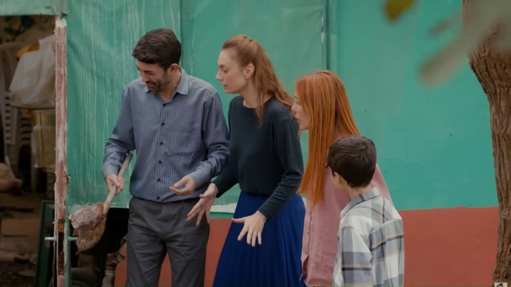 Cemil, Derya, Yonca i Emir patrzą na ziemię z paniką. Cemil trzyma w rękach łopatę. W tle widać wejście do szopy.
