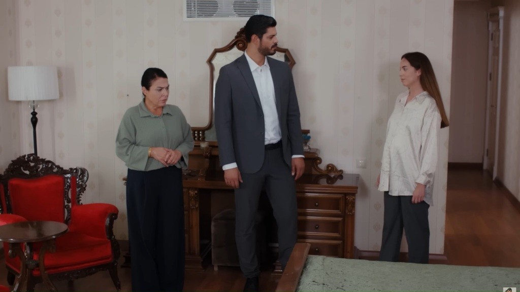 Mukadder Cihan i Beyza stoją w pokoju obok siebie. Mukadder ma splecione z przodu dłonie i lekko spuszczoną głowę, a Cihan patrzy w bok, wbijając wzrok w Beyzę.