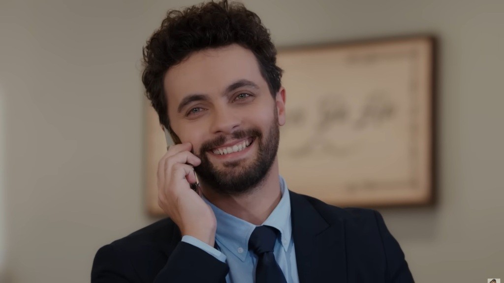 Engin trzyma telefon przy twarzy i uśmiecha się promiennie.
