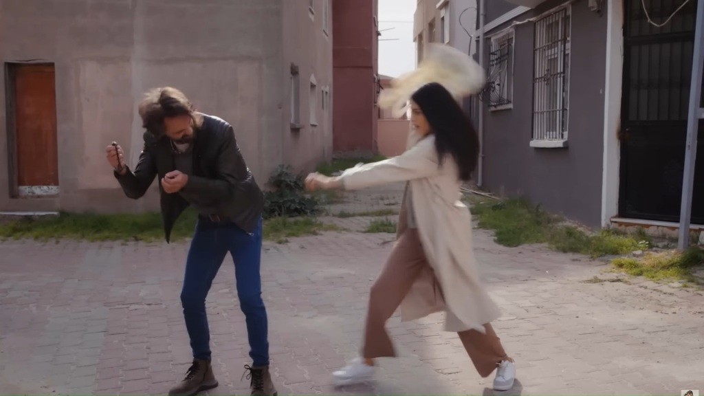 Kobieta uderza torbą mężczyznę w wąskiej uliczce.