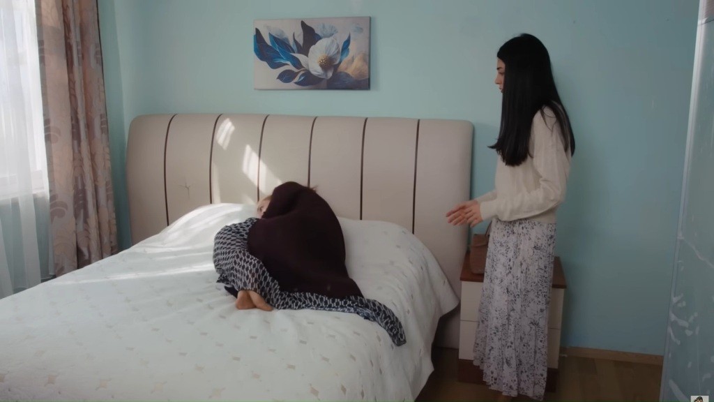 Derya leży skulona na łóżku. Hancer stoi obok gotowa jej pomóc.