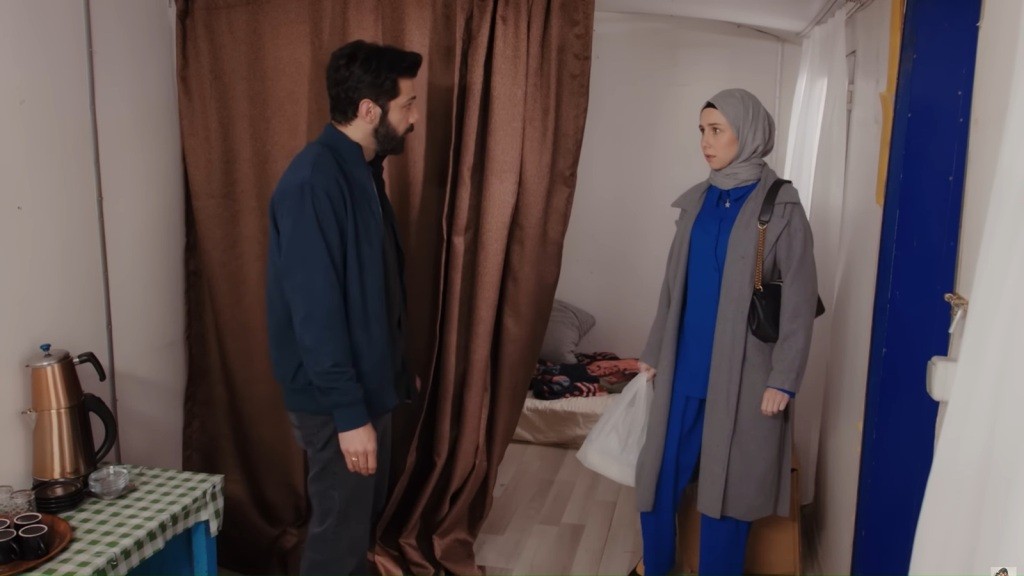 Melih i Sinem stoją naprzeciwko siebie w środku przyczepy, w której panuje nieporządek.