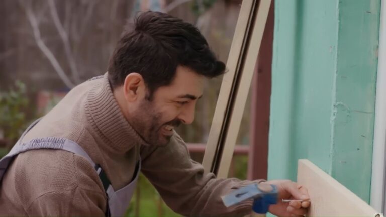 Cemil przybija deskę do ściany.