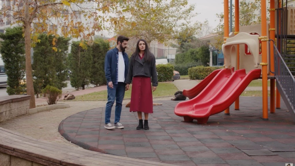 Melih i Hancer stoją obok zjeżdżalni na pustym placu zabaw. Panuje między nimi napięcie.