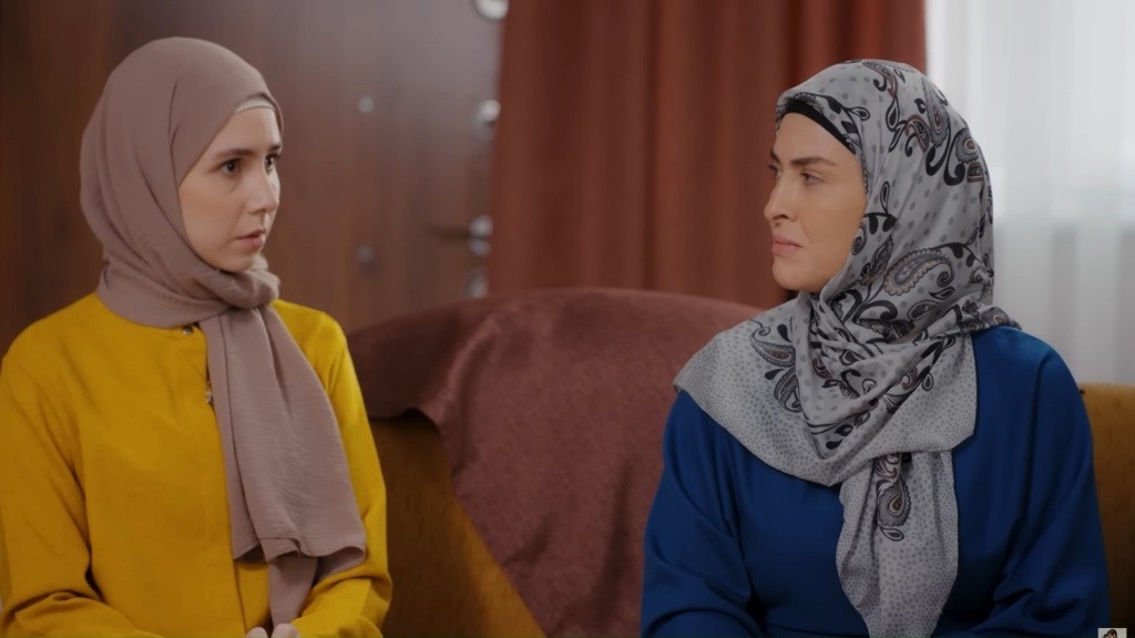 Sinem i jej mama mają na głowie chusty. Matka patrzy na córkę z napięciem, a ta wydaje się zdezorientowana.