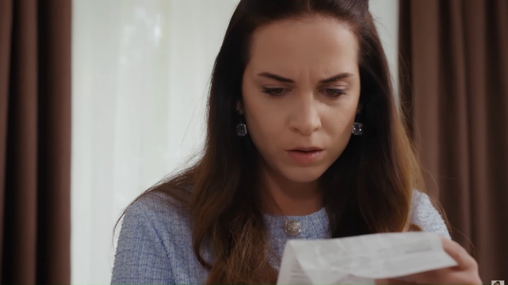 Beyza wpatruje się w trzymaną w rękach kartkę. Sprawia wrażenie zszokowanej.