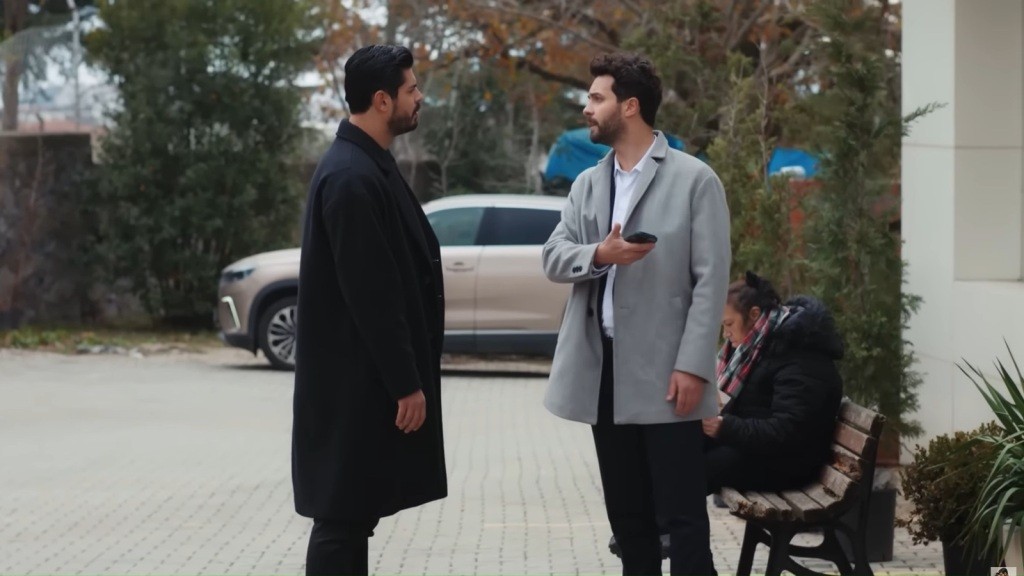 Cihan i Engin stoją naprzeciwko siebie na chodniku. W tle zaparkowany samochód.