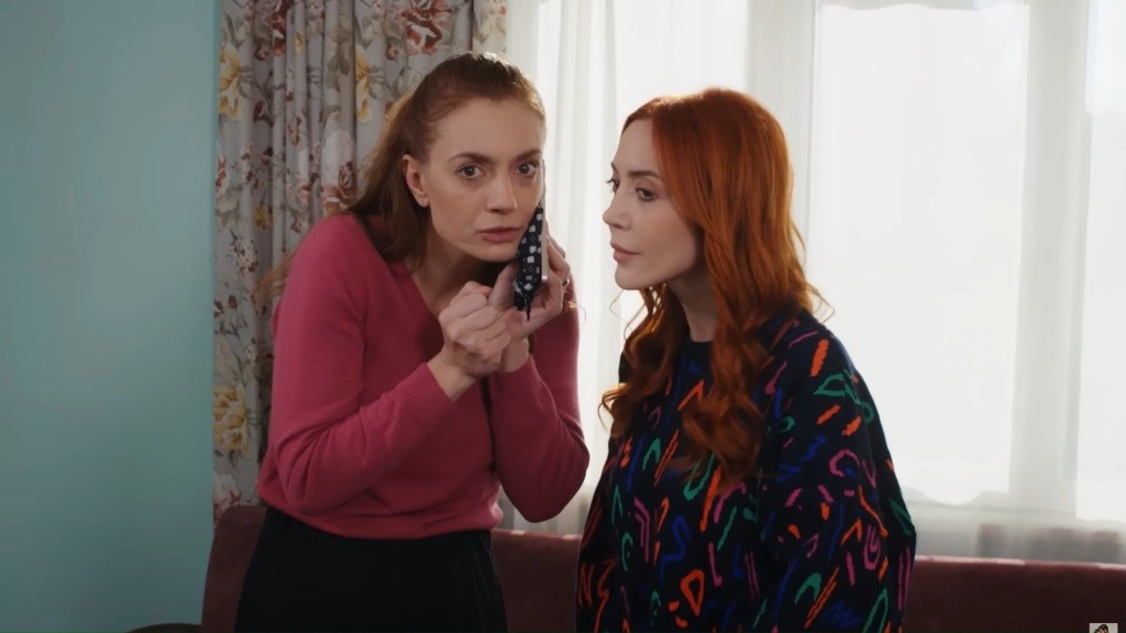 Derya i Yonca są pochylone nad telefonem. Na ich twarzach maluje się skupienie.