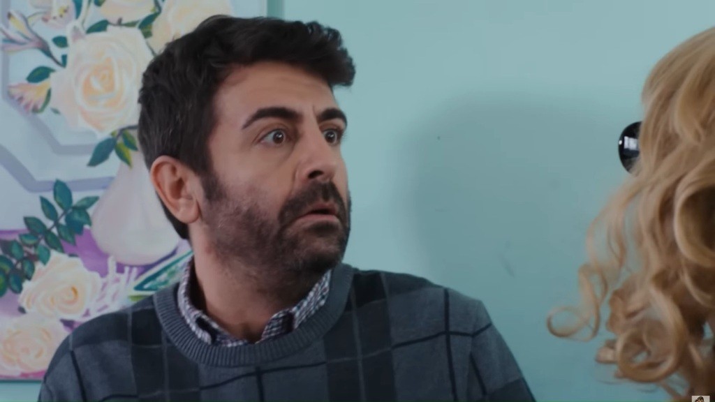 Cemil jest zaskoczony, patrząc na stojącą przed nim kobietę o kręconych blond włosach.