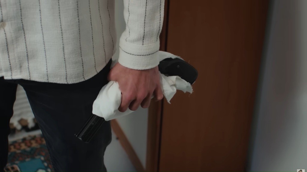 Melih trzyma owinięty w biały materiał pistolet.