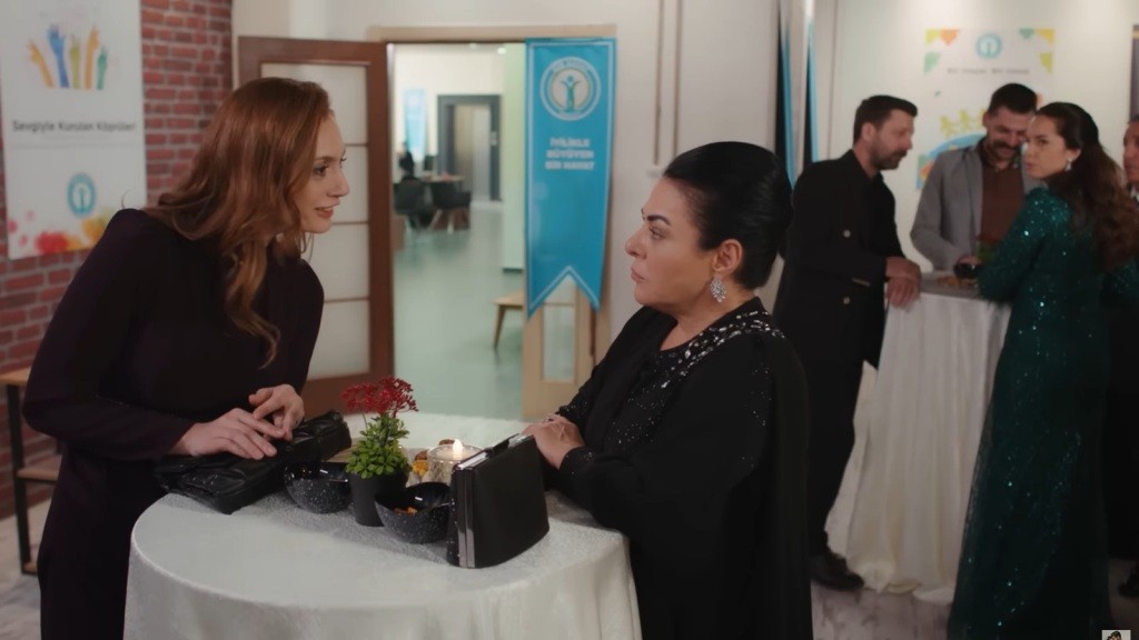 Derya i Mukadder rozmawiają podczas wydarzenia charytatywnego.